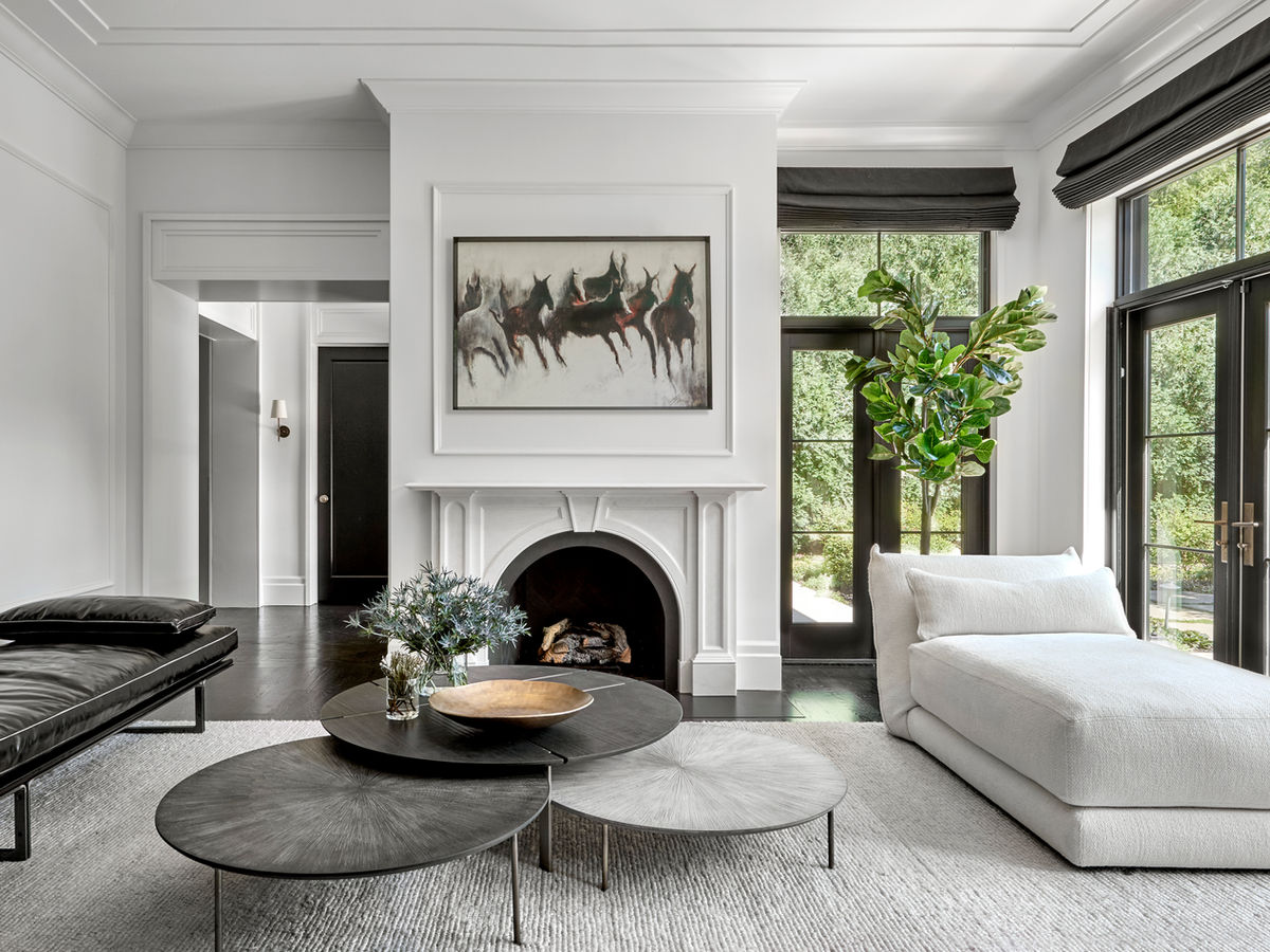 A warm, modern designed room in black and white with a white fireplace and black and white furnishings.
