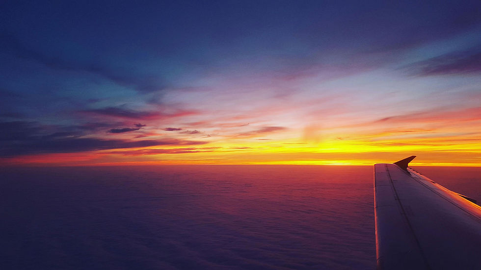 Aerial view of a plane flying above the clouds at sunset - symbolizing the journey from Dublin