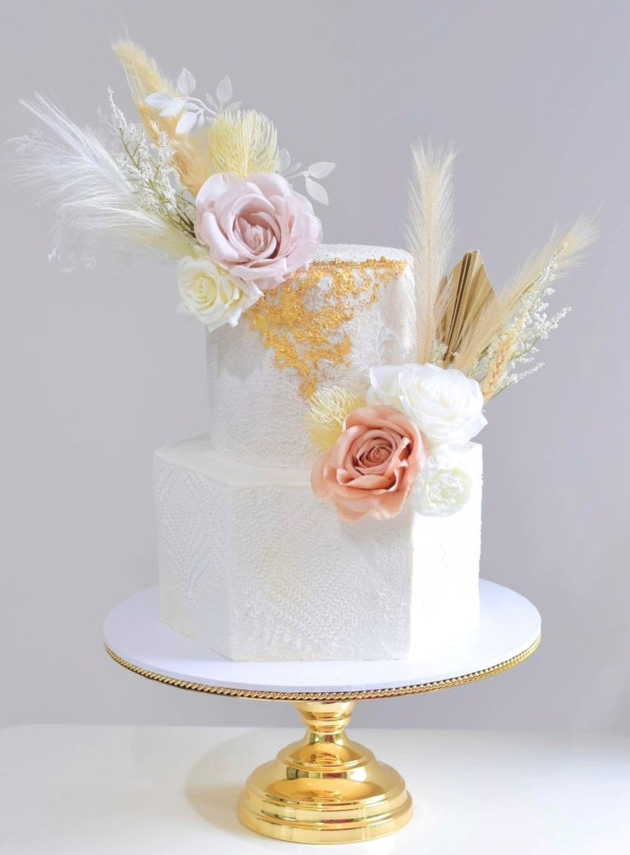 Two tier buttercream wedding cake with hexagon bottom tier. Harvest stencil and gold leaf details.