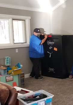 Two movers working beside Cannon Scout and Format gun safes with moving dollies nearby.