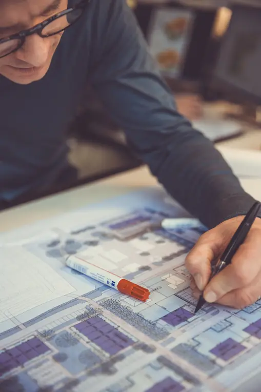Close-up photo of hand pointing at construction drawing and materials