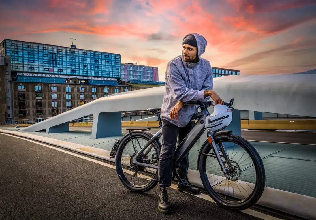 Man op elektrische fiets op brug tijdens zonsondergang