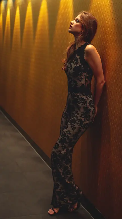 Model poses in evening dress against warm background lighting