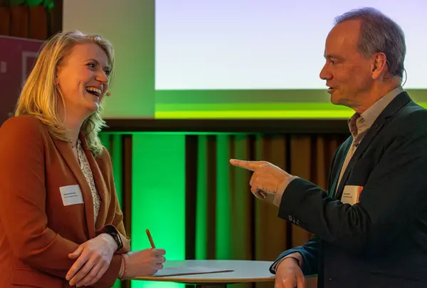 Persoonlijk gesprek tussen professionals tijdens een netwerkmoment in Rotterdam, krachtig in beeld gebracht.
