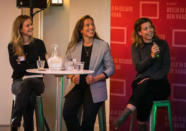 Drie sprekers tijdens een paneldiscussie op een zakelijk evenement in Den Haag.