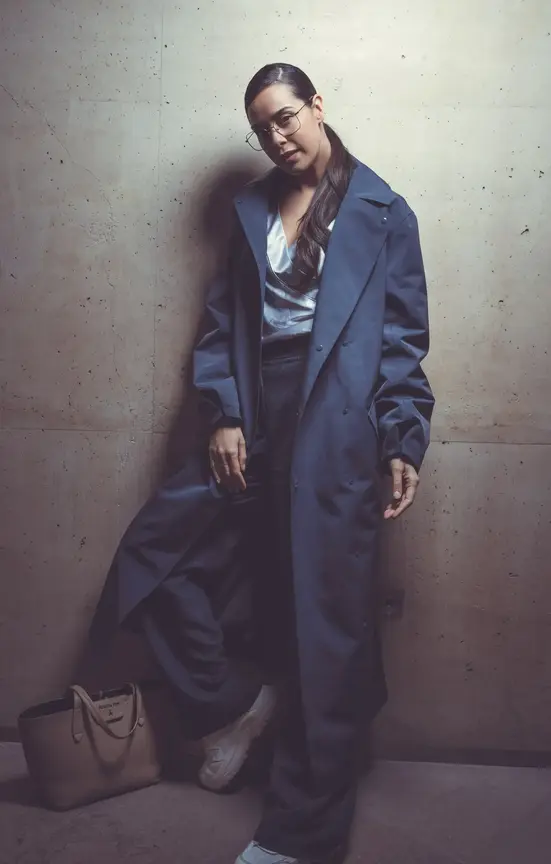 Woman with glasses in casual outfit posing against urban background