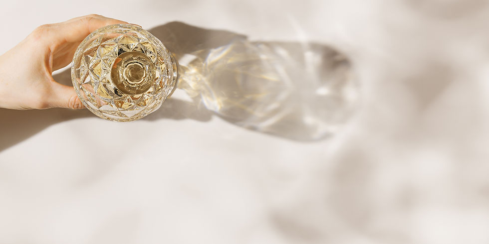 White wine in trend glass in woman hand with shadow at sunlight, beige background and beau