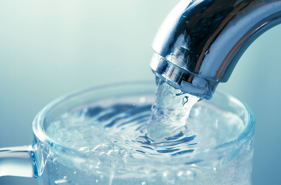 A metal tap fills a glass full of clear drinking water.