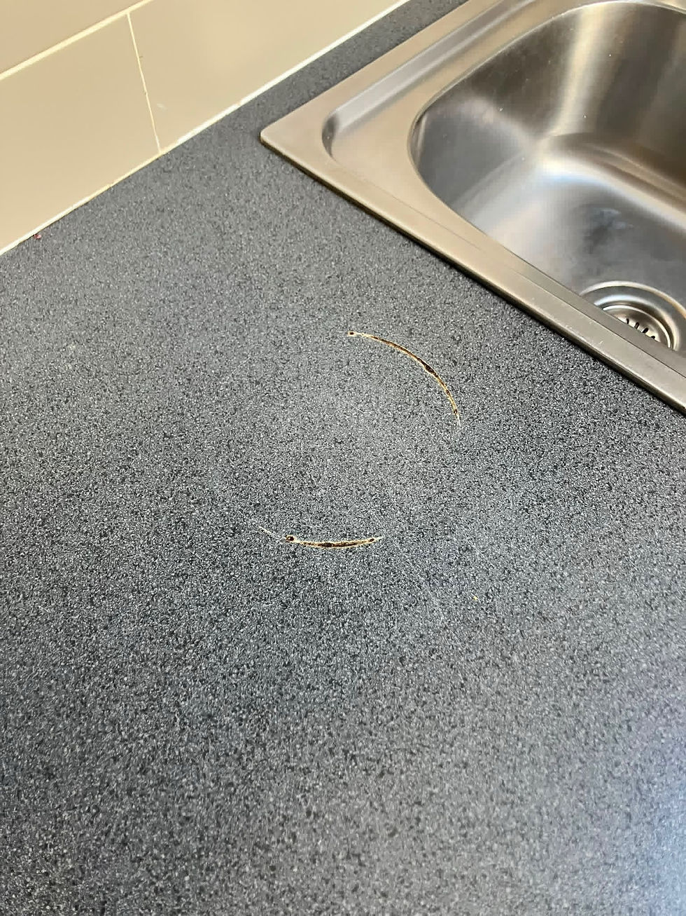 Pan ring burn by the sink on a dark grey speckled laminate worktop in Salford