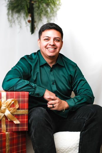 Man in green shirt posing with Christmas gifts during holiday mini session portrait photography in Austin, TX by Ortega Photography