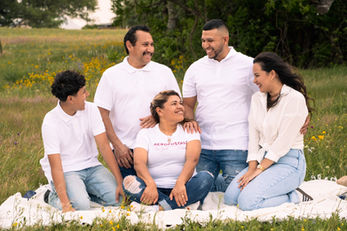 Candid outdoor family portrait of five family members laughing together in a field during family photography session in Austin, TX by Ortega Photography