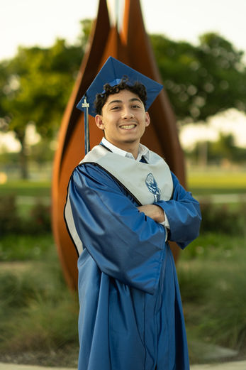 High school male student during the golden hour wearing blue graduation toga and cap in Austin, TX by Ortega Photography.