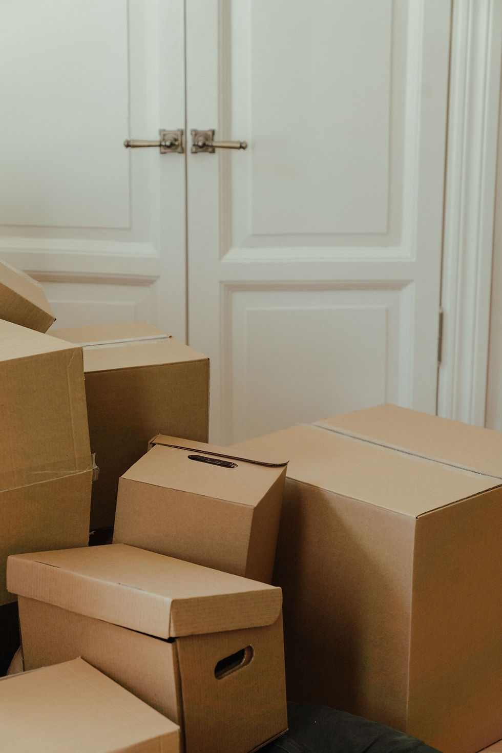 Stack of cardboard moving boxes inside a home next to a white door, ready for a first-time buyer's move