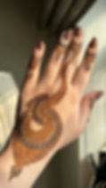 intricate henna mehndi design on left hand with brown nail polish