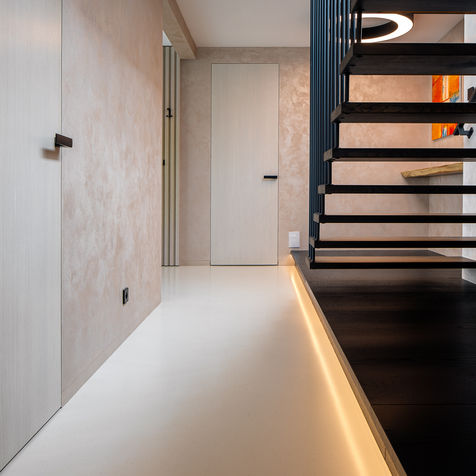 Vstupní hala s černým schodištěm, kruhovým svítidlem a abstraktními obrazy na stěně.