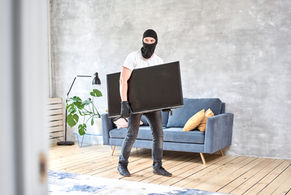 Palm Beach Florida Claims Adjuster - Residential Home Theft Claims | Thief with black balaclava stealing modern expensive television. Masked face. Man burglar