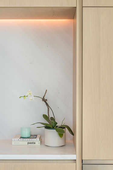 Orchid and books on the kitchen counter beside pale wood cabinetry at The Tampa EDITION.