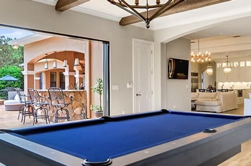Blue billiards table and wood ceiling beams connect the game room to the adjoining lounge and outdoor terrace.