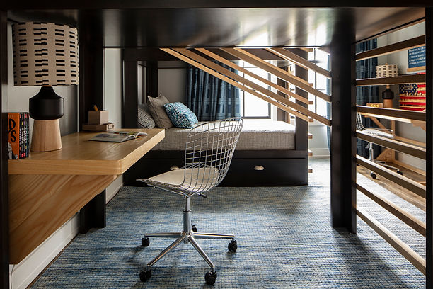 Bunk bedroom detail with a wood desk shelving and a wire chair at Golf View Tampa.