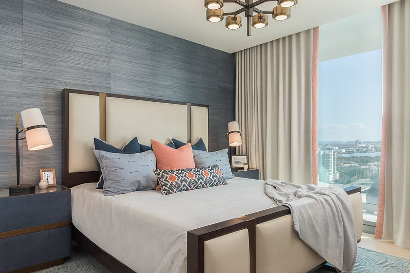 Secondary bedroom at The Tampa EDITION with a blue feature wall and blue and coral cushions.