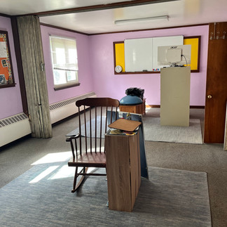Purple classroom, dirty carpet, furniture in middle
