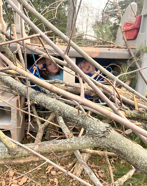 Children in a fort covered in branches