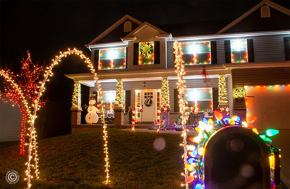 A tunnel of lights and the house decorated for Christmas.