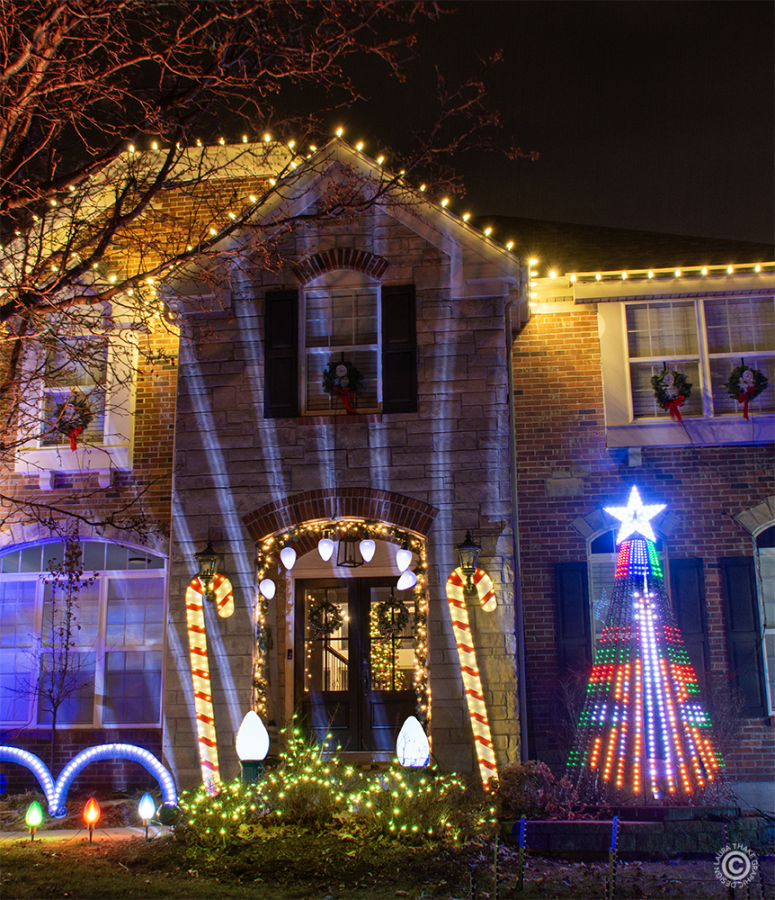 Shining bright lights and a Christmas tree visible inside the front door.
