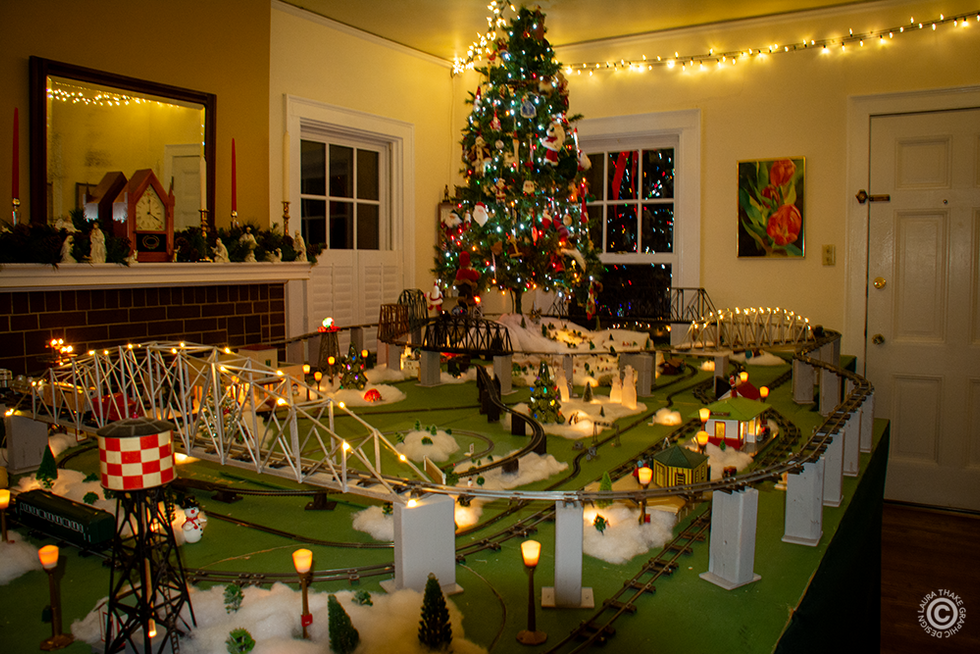 The living room of the home has 7 trains set up and running.