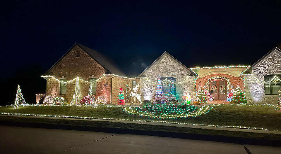 The left side os the house and yard are lit up with trees and shrubs.