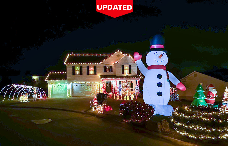 A 20 foot tall Snowman inflatable standing in front of a house covered in Christmas lights.