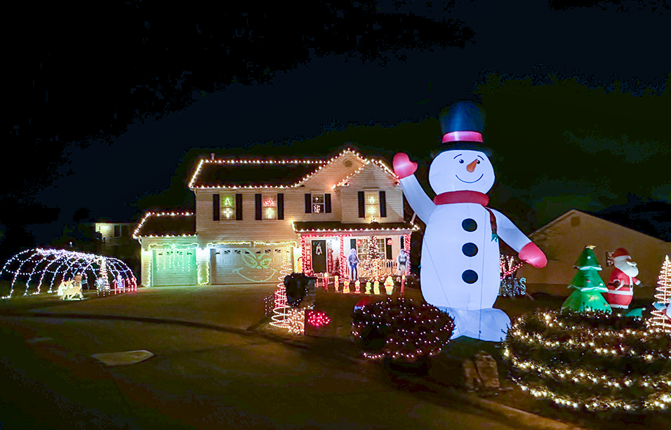 A 20 foot tall Snowman inflatable standing in front of a house covered in Christmas lights.