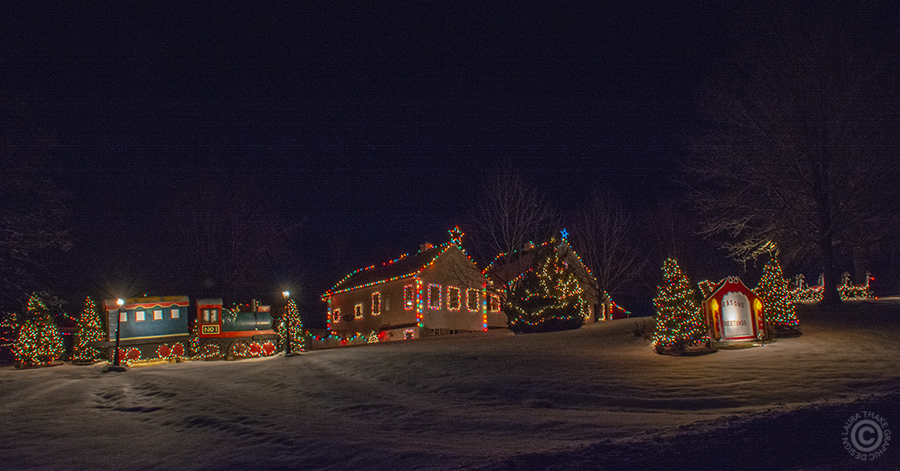 Christmas train in front of a house decorated for Christmas.