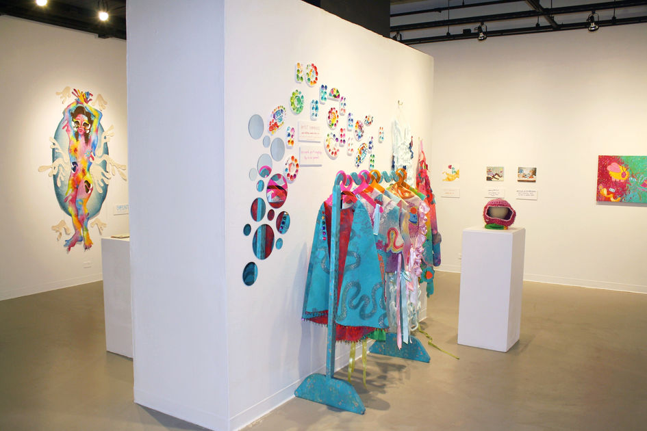 a clothes rack and mirrors, and several colorful paintings line the walls of the gallery