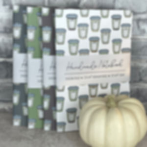 Four handmade saddle bound notebooks with hand drawn pumpkin spice coffee cups arranged in a vertical pattern on the covers.