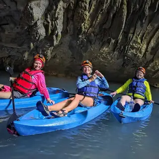 Kayakers paddling into a limestone cave entrance on the Caves Branch River, Belize