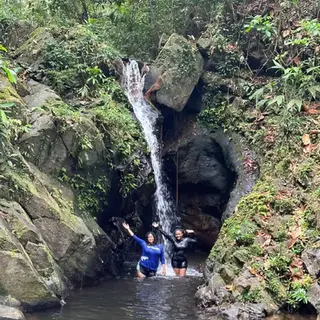 Guests swimming beneath a jungle waterfall at Ben's Bluff, Cockscomb Basin, Belize.