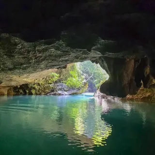 Sunlight streaming through a cave mouth onto turquoise water, Caves Branch River