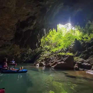 Sunlight streaming through an opening in a river cave during a cave kayaking tour from Hopkins Village, Belize