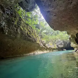 Jungle-framed cave mouth on the Caves Branch River during a guided cave kayaking tour in Belize
