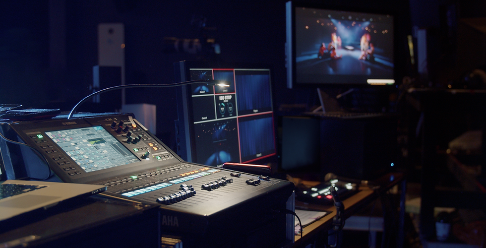 A sound mixer and a video switcher with monitors showing a production in a studio