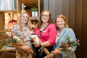 three women holding bouquets of flowers with one wearing a name tag