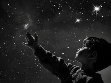 young boy reaching up to starry sky