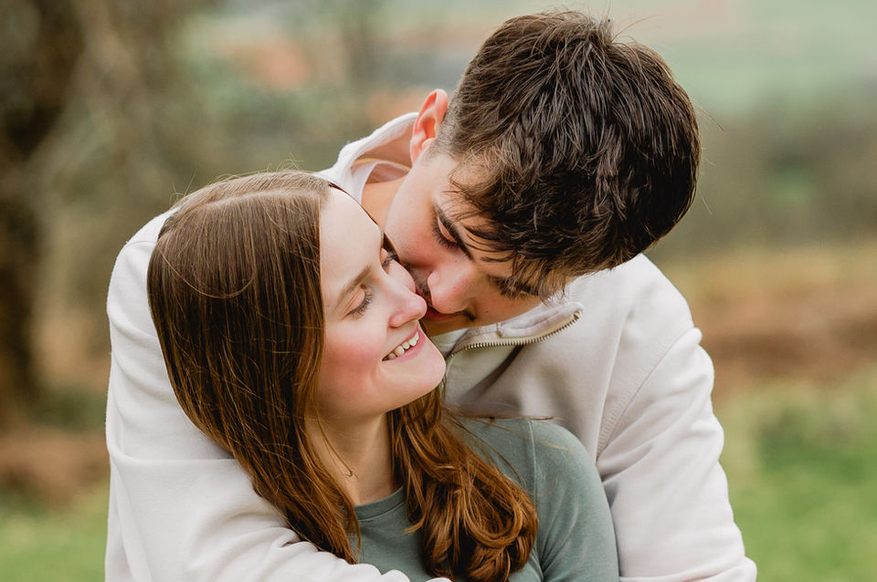 A young couple hugging and smiling on the Quantock Hills in Somerset.