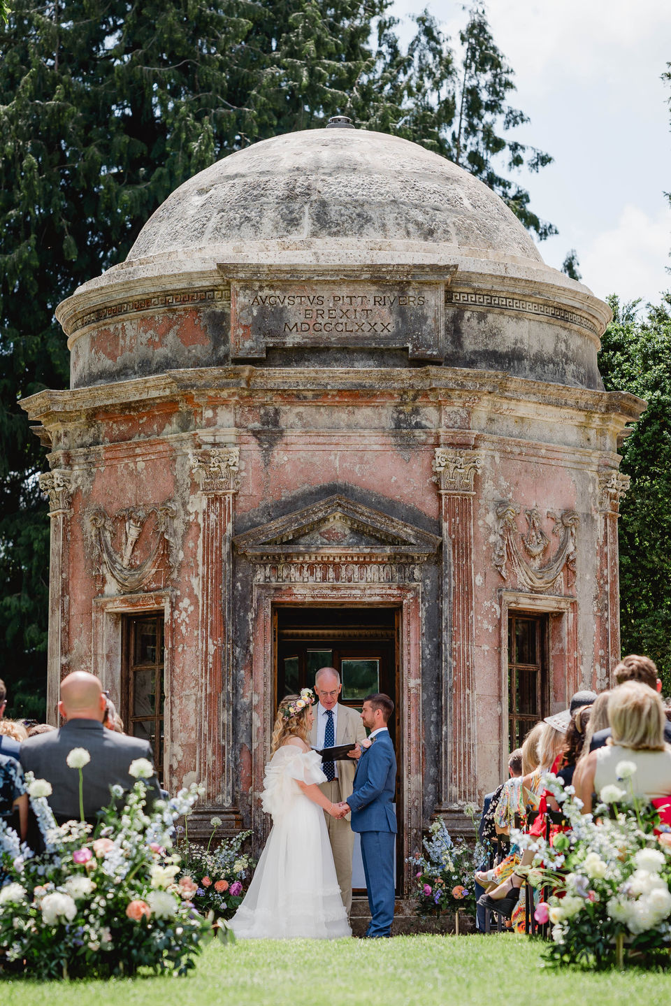 Emotional outdoor wedding ceremony as bride and groom exchange vows at the Roman Temple, Larmer Tree Gardens, Salisbury, Wiltshire.