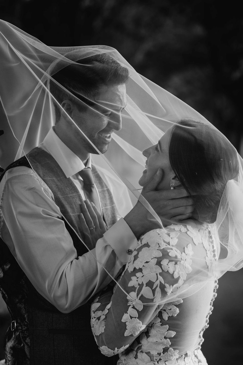 Romantic black and white photo of a bride and groom laughing under her veil at the Tithe Barn, Hinton St Mary Estate – a stunning wedding venue in Dorset.