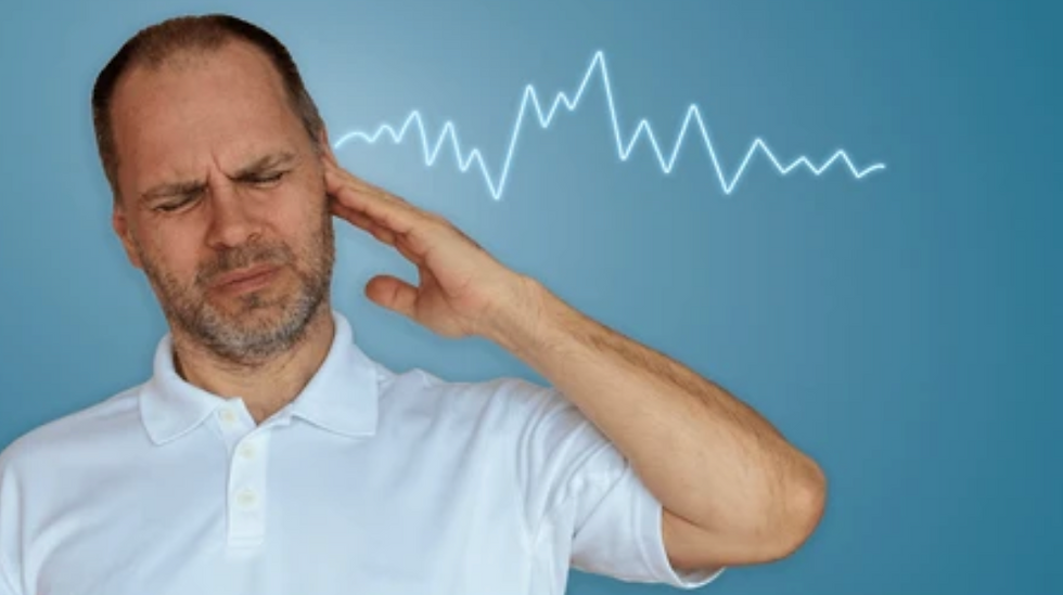 Man suffering from tinnitus and ringing in the ear.