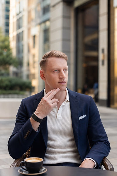 Jesper in a navy blazer seated at an outdoor café.