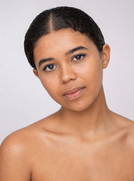 Bare-shouldered portrait of Lydia with slicked-back hair and a cobalt blue winged eyeliner stroke