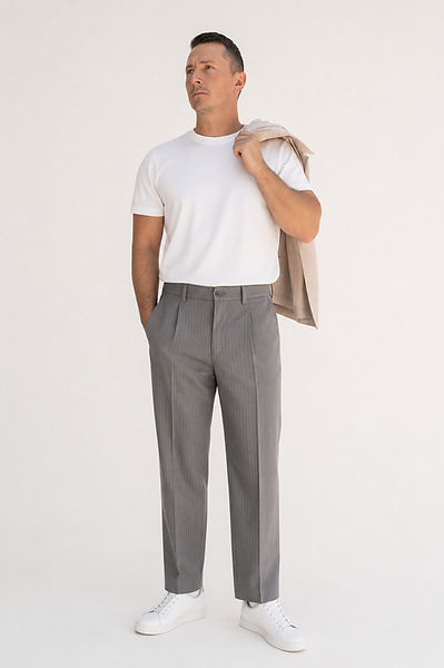 Craig Mulgrew, model, in a white t-shirt and grey pinstripe trousers with a tan jacket over his shoulder.